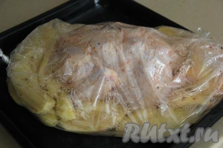 Поверх долек картошки выложить курицу целиком, завязать концы рукава с двух сторон. Сделать в рукаве с помощью зубочистки несколько проколов. Поставить противень в хорошо прогретую духовку.