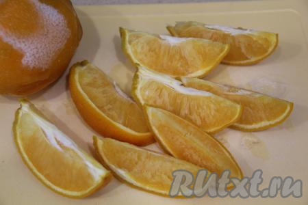 Замороженные апельсины достать из морозилки, немного разморозить, чтобы можно было их разрезать ножом и нарезать на крупные дольки вместе с кожурой.