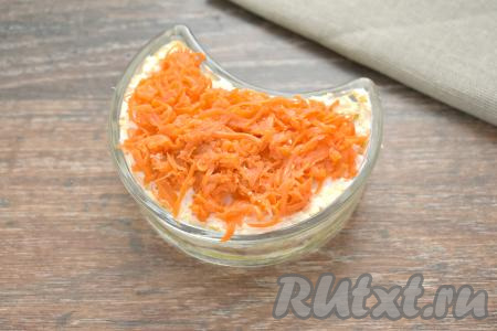 Завершающим слоем салата "Лисья шубка" выкладываем морковку, натёртую на крупной тёрке. Аккуратно распределяем морковь по поверхности салата.