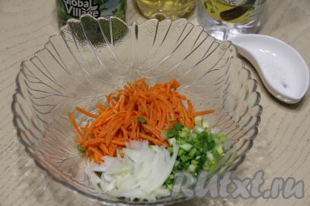 Если полоски корейской моркови длинные, тогда разрежьте морковку на несколько частей. В салатник выложить корейскую морковь, добавить тонко нарезанный репчатый лук и мелко нарезанный зелёный лук.