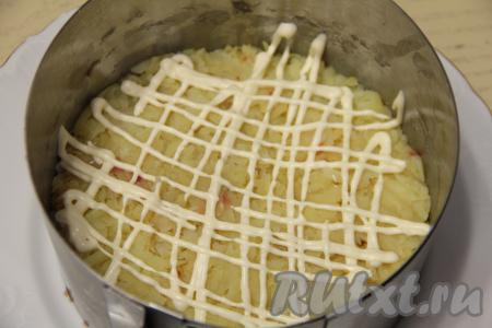 Следующим слоем равномерно распределить картофель, натёртый на крупной тёрке, слегка утрамбовать, можно немного подсолить, затем нанести сетку из майонеза.