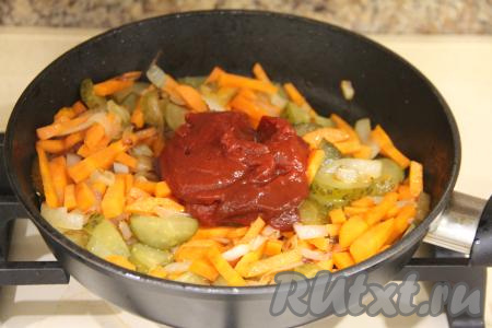 Обжаривать огурчики с морковкой и луком минуты 3, затем добавить томатную пасту.
