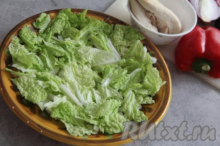 Пекинскую капусту крупно нарезать и выложить на плоскую тарелку, в которой будете подавать греческий салат.