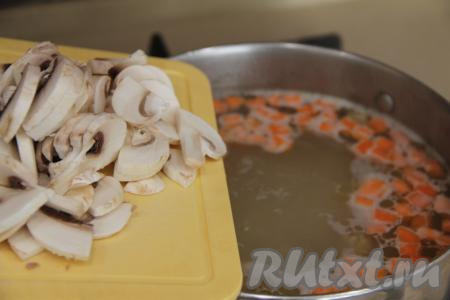 Промыть шампиньоны водой, нарезать на пластины. После того как куриный суп с рисом проварится 15 минут, добавить в кастрюлю шампиньоны, дать закипеть и варить 10 минут на небольшом огне.