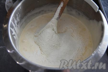 Добавить медово-масляную смесь в чашу со взбитыми яйцами и перемешать лопаткой до однородности. Затем в несколько приёмов всыпать просеянную муку, каждый раз тщательно вмешивая её в тесто.