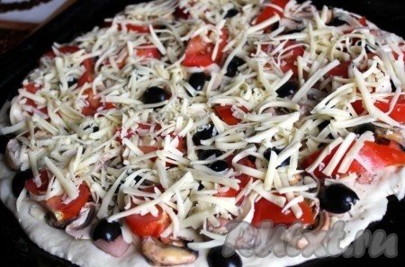 Осталось посыпать пиццу с морепродуктами сыром и поставить в разогретую до 200-220 градусов духовку на 15 минут.