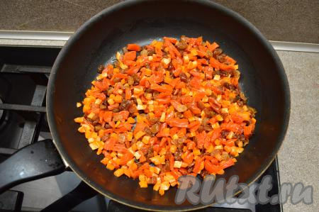 К морковке, обжаренной до мягкости, добавить изюм и нарезанную курагу, всыпать корицу, перемешать и обжаривать 2-3 минуты, иногда помешивая.
