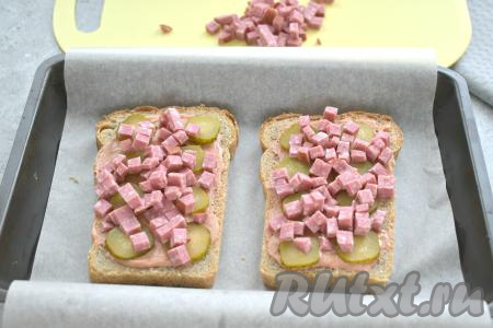 Поверх огурцов равномерно раскладываем колбасу, нарезанную на маленькие кубики.