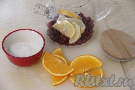 Нарезать апельсины и лимоны на полукружочки. В чайник выложить чай, клюкву, полукружочки лимона и апельсина, всыпать сахар. При желании фрукты и овощи можно слегка помять столовой ложкой.