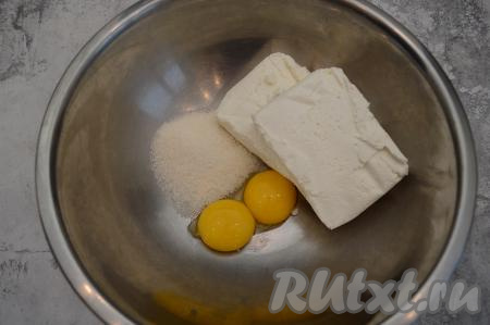 В глубокую миску выложить желтки, творог и сахар.