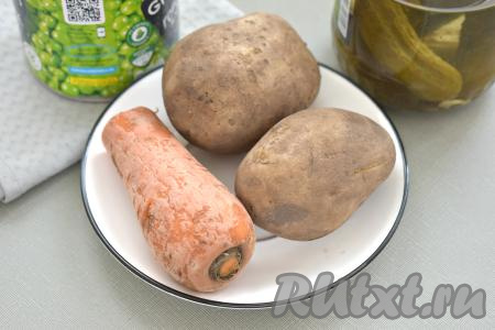 Чтобы приготовить постный салат "Оливье" с маринованными грибами, заранее отвариваем картошку и морковь в кожуре до готовности, затем аккуратно достаём овощи из воды, выкладываем на тарелку и даём им остыть. На отваривание картошки до готовности потребуется с момента закипания воды примерно 20-25 минут, а морковка будет готова через минут 30-35 после начала кипения воды. Полностью готовые варёные овощи будут легко прокалываться вилкой.