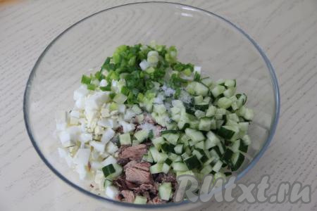 В салатник с рисом и яйцами добавить огурец, тунца и мелко нарезанный зелёный лук, посолить.