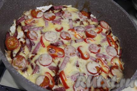 Затем разложить равномерно в один слой колбасу, помидоры и болгарский перец, присыпать сверху сыром, натёртым на крупной тёрке. Накрыть сковороду крышкой и готовить пиццу из рваного лаваша на медленном огне минут 10-15. Сыр должен полностью растопиться.