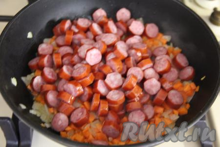 Охотничьи колбаски нарезать на кружочки, добавить к обжаренным овощам, перемешать. Обжаривать колбаски с овощами 2-3 минуты, периодически перемешивая.