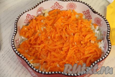Следующим слоем равномерно выложить очищенную и натёртую на крупной тёрке варёную морковь.