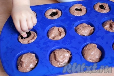 Разложите тесто по смазанным формочкам или по силиконовым и в каждый кекс добавьте начинку. Тут чернослив, а в следующих двенадцати кексах - кусочки шоколада.
