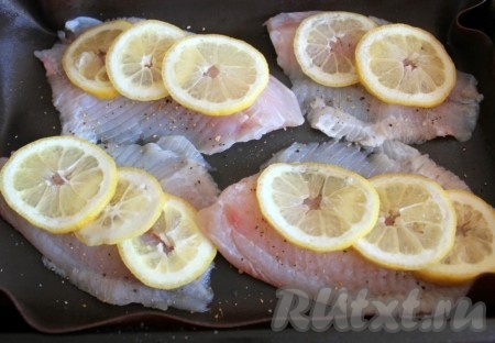 Лимон нарезать тонкими кружочками и выложить его слоями на филе рыбы.