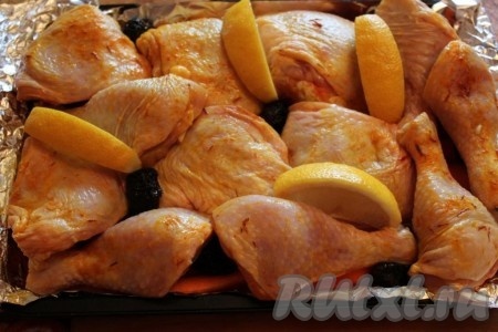Затем в один слой положить куски курицы и между ними разместить дольки лимона и ещё чернослив.