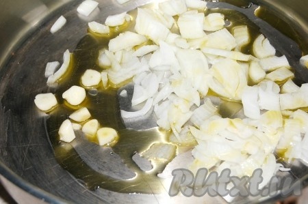 Налить на сковороду оливковое масло и обжарить в нем мелко нарезанные репчатый лук и чеснок.