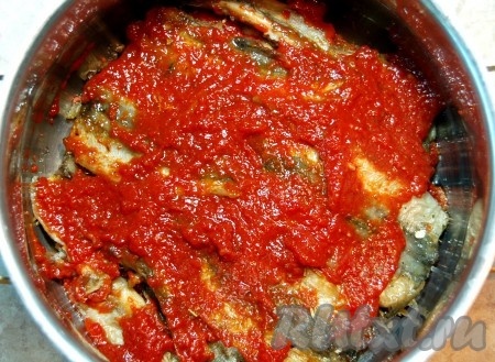 Затем выложить оставшийся томатный соус, покрывая всю рыбку, влить горячую воду (вода должна покрывать мойву), поставить на огонь. После закипания соус, если нужно, досолить, уменьшить огонь, накрыть кастрюлю крышкой и тушить мойву 30 минут.
