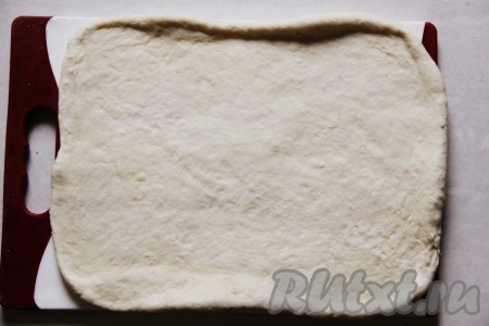 Разделить тесто на два равных кусочка. В будущем это будет 2 хлеба. Если хотите, то можно разделить на три части или сделать один большой круглый хлеб. Каждую часть раскатать скалкой или растянуть руками по доске. В итоге должен получиться прямоугольник из теста.