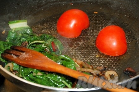 Обжаривать все вместе 1 минуту, затем содержимое сковородки сдвинуть на одну сторону. На свободное место положить разрезанные пополам помидоры срезом вниз и слегка их обжарить.