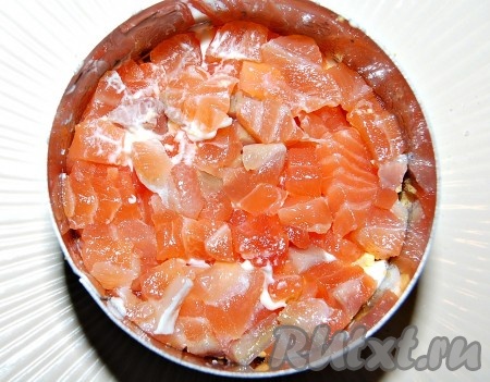 Соленую рыбу мелко нарезать и половину порции уложить на слой из желтков. Этот слой также смазать небольшим количеством майонеза.
