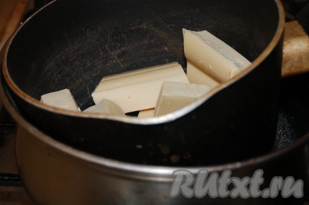 Пока песочный пирог остывает, нужно сделать сладкую начинку. Для этого в небольшой ковшик поломать белый шоколад и на водяной бане растопить его.

