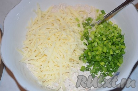 К масляно-мучной крошке добавить сыр, натёрный на крупной тёрке, и мелко нарезанный зелёный лук, перемешать ложкой.
