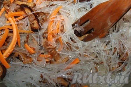 Добавить кусочки рисовой вермишели и морковь в кастрюлю к грибам и перемешать все вместе.
