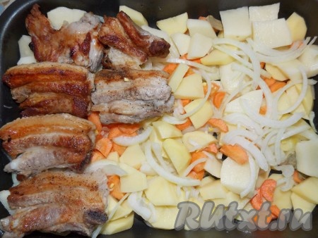 Чеснок и лавровый лист положить на противень к картошке, затем выложить свиные ребрышки.
