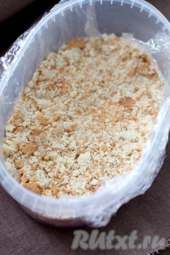 Застелите пищевой пленкой форму и выложите бисквит хорошо утрамбовав. Разъемную форму можно застелить пергаментом.