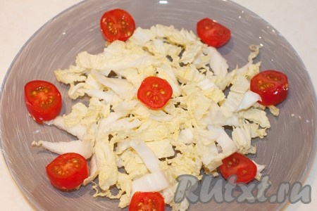 Нашинкуйте капусту и выложите на блюдо, добавив половинки помидоров черри.
