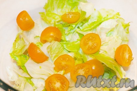 В салатник выложите листья салата и половинки помидоров черри.
