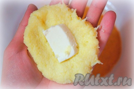 Влажными руками взять немного картофельного теста, сделать из него лепешку, в центр которой положить 1-2 кусочка сыра.
