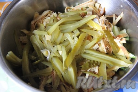 Маринованные огурцы нарезать соломкой, отжать от  лишнего сока и добавить в миску с салатом.