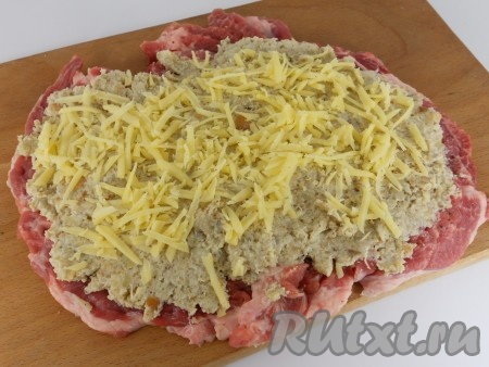 Разложить начинку по всей поверхности отбитого мяса. Сверху посыпать натёртым на тёрке сыром и натёртым на мелкой тёрке чесноком.