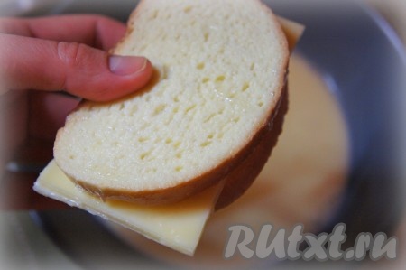 Быстро обмакните получившийся бутерброд в молочно-яичную смесь с одной и с другой стороны. Излишкам молочно-яичной смеси дайте стечь. Аналогично подготовьте второй бутерброд с сыром.