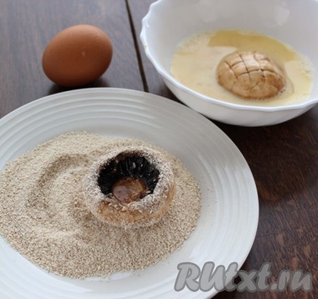 Взбить яйцо вилкой. Приготовить панировку, это может быть кукурузная мука или сухари панировочные. Шляпки грибов окунуть в яйцо и обвалять в панировке.