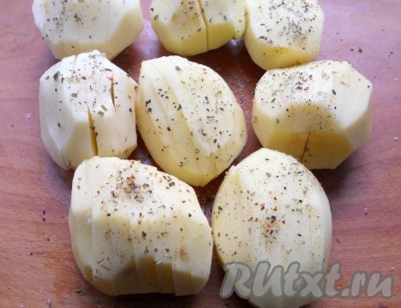 Картофель среднего размера очистить. Сделать по 5-6 надрезов на каждой картофелине, не прорезая до конца, посолить, поперчить, посыпать специями.