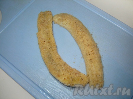 Очистите банан от кожуры. Разрежьте его вдоль на две половинки. Обсыпьте половинки бананов панировочными сухарями.