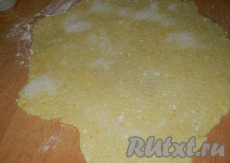 На присыпанной мукой поверхности раскатываем тесто в тонкий пласт, смазываем мягким сливочным маслом (примерно 10 граммами) и посыпаем 5-6 столовыми ложками сахара.