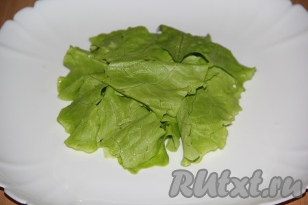 Листья салата вымыть, обсушить и порвать на небольшие кусочки. Выложить листья салата на плоскую тарелку.
