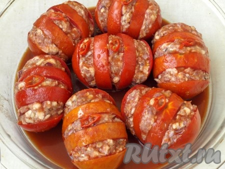 Форму для запекания смазать растительным маслом и выложить помидоры. Положить сверху колечко горького перца на каждый помидор. В воду добавить томатную пасту, хорошо размешать и полить помидоры.
