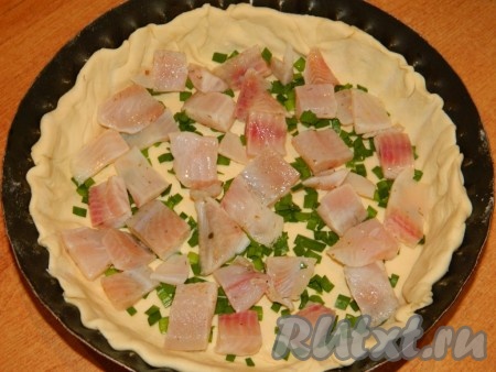 На тесто выложить нарезанное рыбное филе.