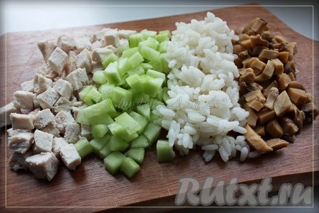 Рис и куриную грудку отварить до готовности. Огурцы очистить от шкурки и удалить семена. Порезать кубиками курицу, огурцы и шампиньоны.
