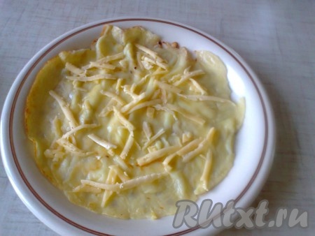Тем временем, по любому вашему любимому рецепту жарим блины. Натираем сыр на мелкой тёрке. На блинчик насыпаем немного сыра.