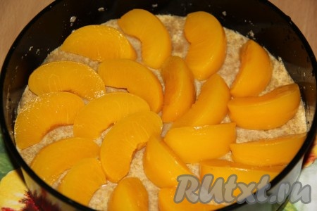 Достать форму из холодильника, поверх коржа выложить кусочки персиков.