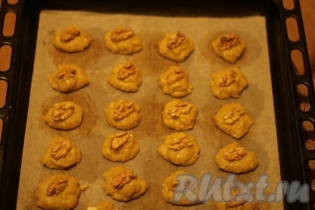 С помощью столовой ложки выкладываем печенье на бумагу для выпечки. Украшаем орехами.
