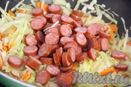  Колбасу нарезать на кружочки, добавить к овощам, хорошо перемешать и тушить под крышкой 5 минут.